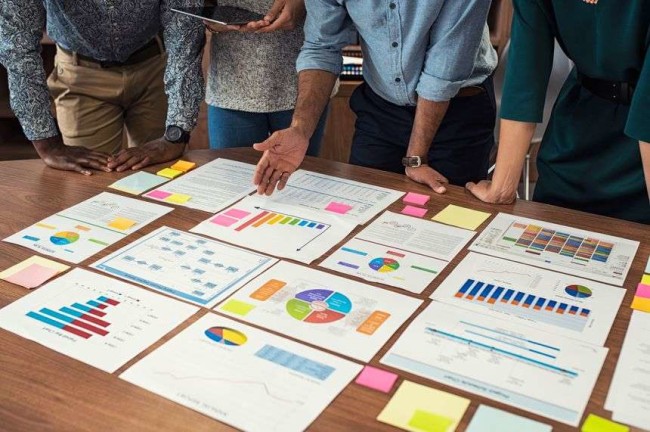 웹사이트 개선 가이드 목표 및 성과 A team looking at the website improvement goal achievements and metrics on the table