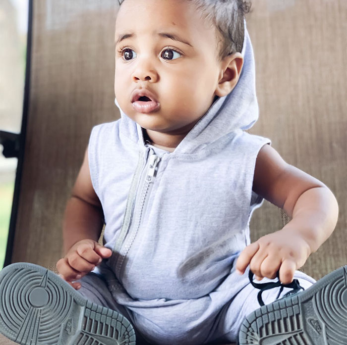 Bebé con capucha gris sin mangas y zapatillas Nike